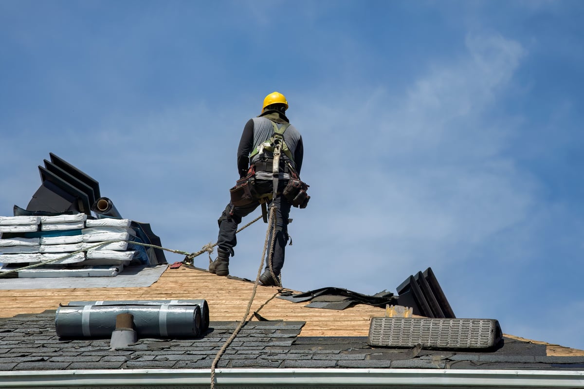 Roofing contractor installing shingles on new home